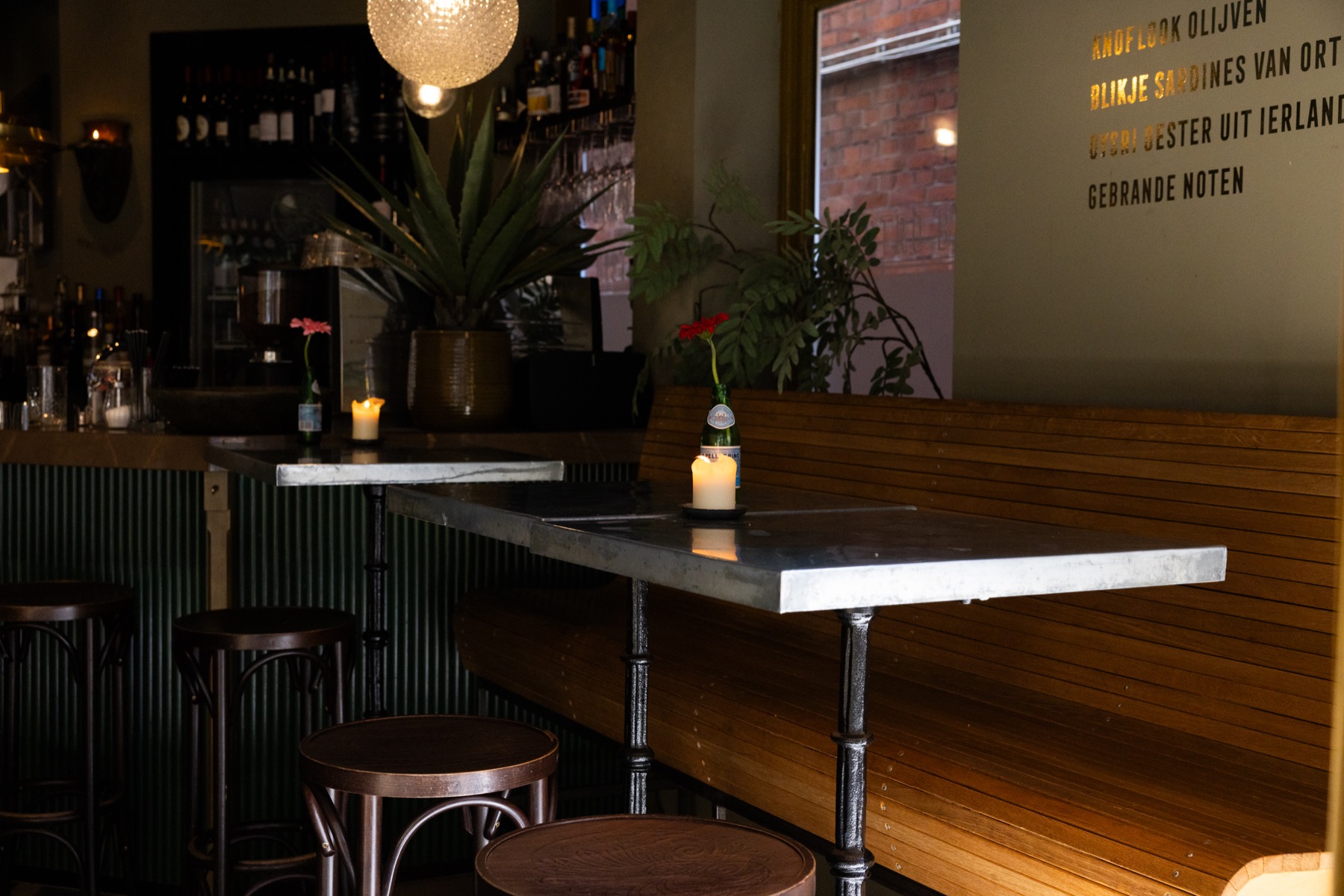De bank en de hoge tafels in Bistro Boys, met een bloem in een flesje