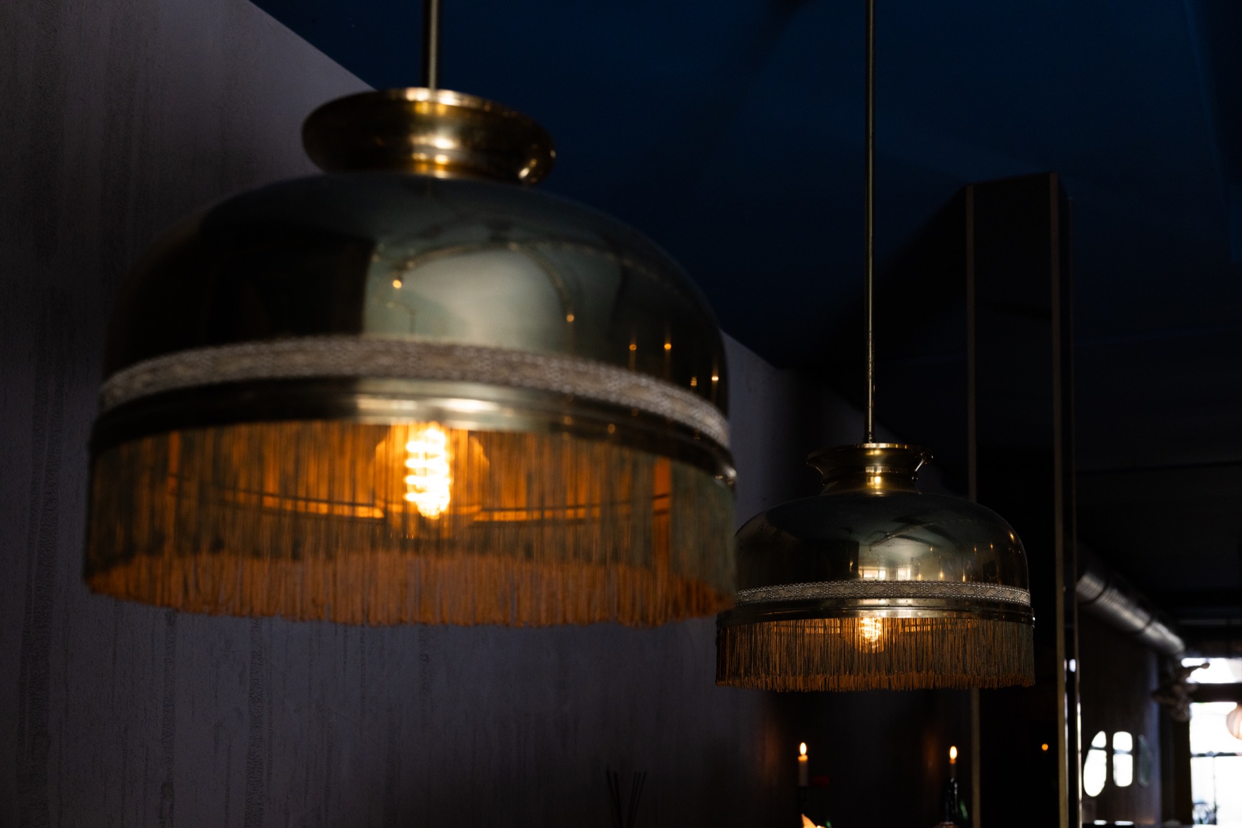 De gouden lampen met franje boven de bar
