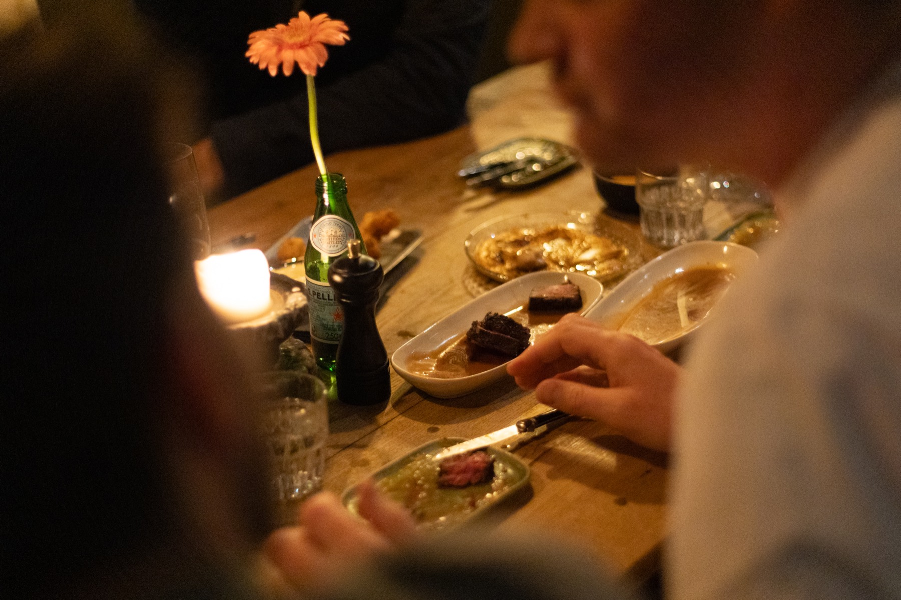 Een gerbera in een flesje op een volle tafel